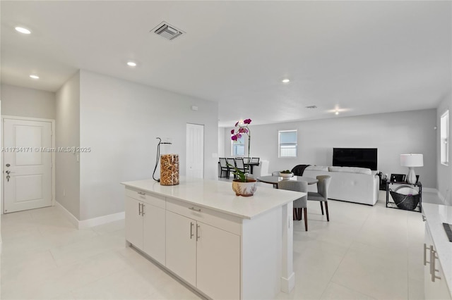 kitchen with light tile patterned floors, a kitchen island, and white cabinets