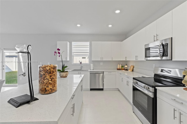 kitchen featuring light stone counters, stainless steel appliances, sink, and white cabinets