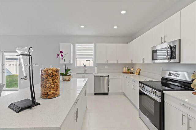 14823 SW 163rd Ter, Miami, FL 33187 - kitchen featuring appliances with stainless steel finishes, a sink, a center island, recessed lighting, and light stone countertops