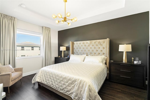 bedroom featuring an inviting chandelier, a tray ceiling, and dark hardwood / wood-style flooring