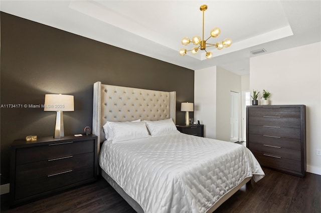 bedroom featuring a chandelier, dark hardwood / wood-style flooring, and a tray ceiling