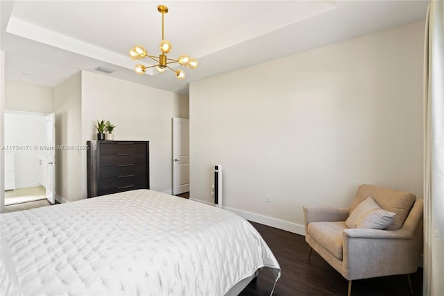 bedroom featuring a tray ceiling, dark wood-type flooring, and a chandelier