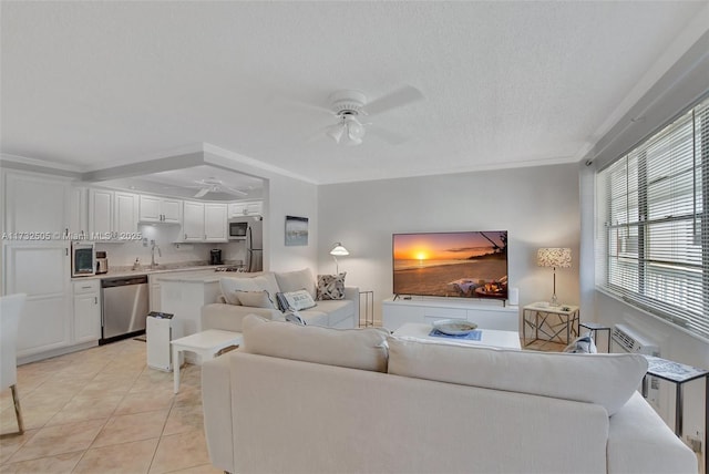 living room with sink, light tile patterned floors, ceiling fan, crown molding, and a textured ceiling