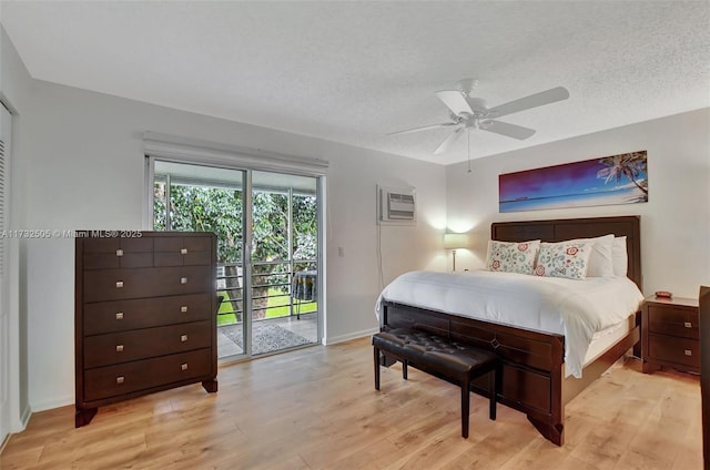 bedroom featuring a wall mounted AC, a textured ceiling, access to outside, ceiling fan, and light hardwood / wood-style floors