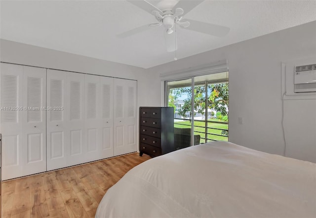 bedroom featuring hardwood / wood-style floors, a wall mounted AC, access to outside, ceiling fan, and a closet