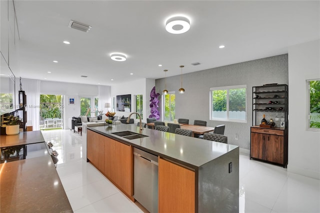 kitchen with pendant lighting, sink, light tile patterned floors, dishwasher, and a large island with sink