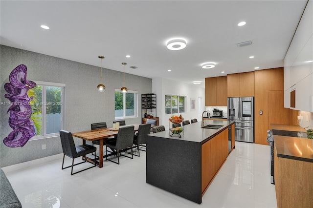 kitchen featuring stainless steel appliances, an island with sink, sink, and decorative light fixtures