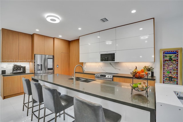 kitchen with white cabinetry, appliances with stainless steel finishes, sink, and tasteful backsplash