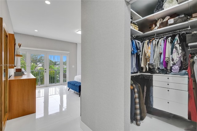 walk in closet with light tile patterned floors and french doors