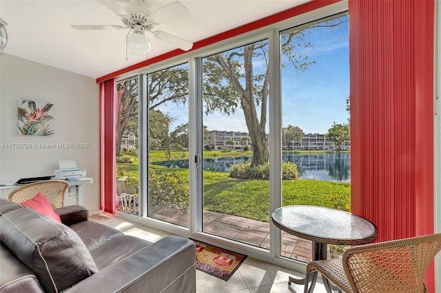 sunroom featuring ceiling fan and a water view