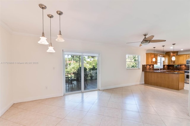 unfurnished living room featuring ornamental molding, baseboards, ceiling fan, a sink, and light tile patterned floors