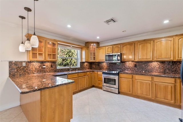 kitchen featuring sink, appliances with stainless steel finishes, dark stone countertops, hanging light fixtures, and kitchen peninsula