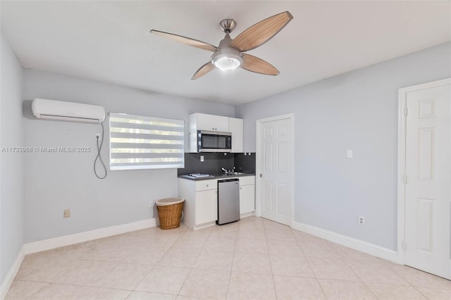 kitchen with appliances with stainless steel finishes, a ceiling fan, white cabinetry, backsplash, and a wall mounted AC