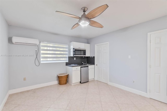 kitchen featuring ceiling fan, appliances with stainless steel finishes, a wall mounted AC, white cabinets, and decorative backsplash