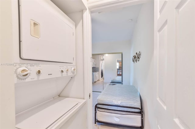 laundry room with light tile patterned floors, laundry area, and stacked washer / dryer