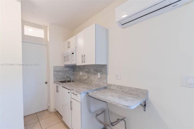 kitchen with tasteful backsplash, an AC wall unit, light tile patterned floors, and white cabinets