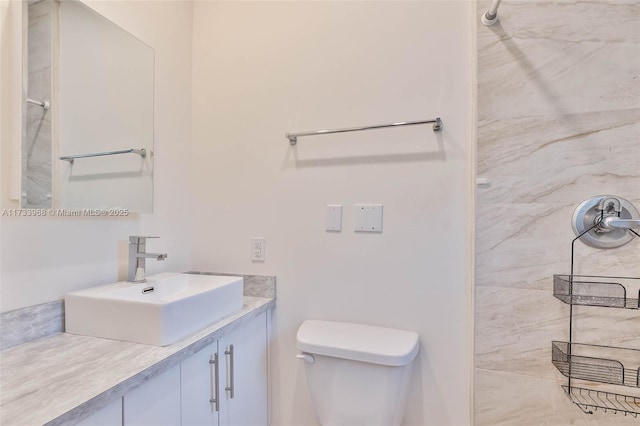 bathroom with vanity, a tile shower, and toilet