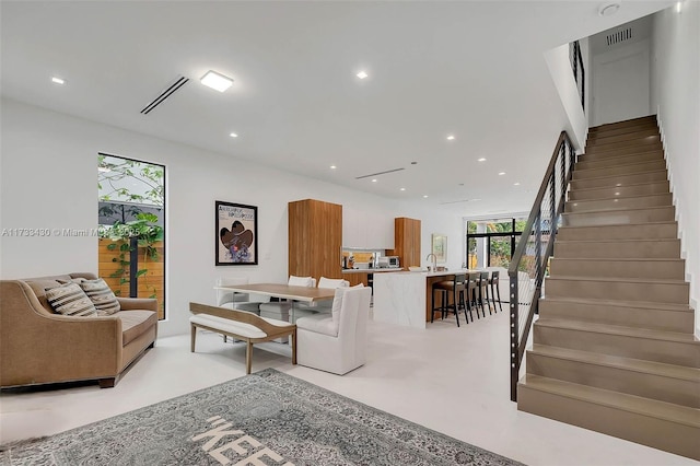 living area with stairway, recessed lighting, finished concrete flooring, and visible vents