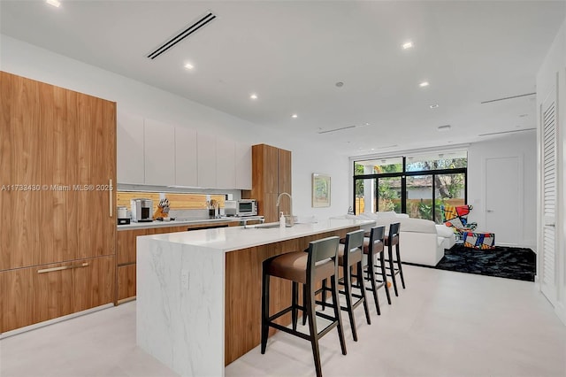 kitchen featuring visible vents, modern cabinets, concrete floors, and a sink