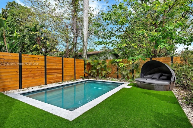 view of swimming pool featuring a lawn and a fenced backyard