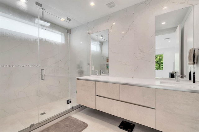 bathroom featuring double vanity, visible vents, a marble finish shower, and a sink