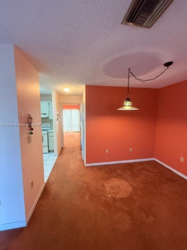 carpeted empty room featuring a textured ceiling