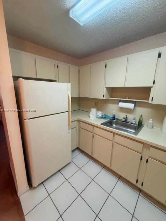 kitchen with sink, cream cabinetry, a textured ceiling, and white fridge