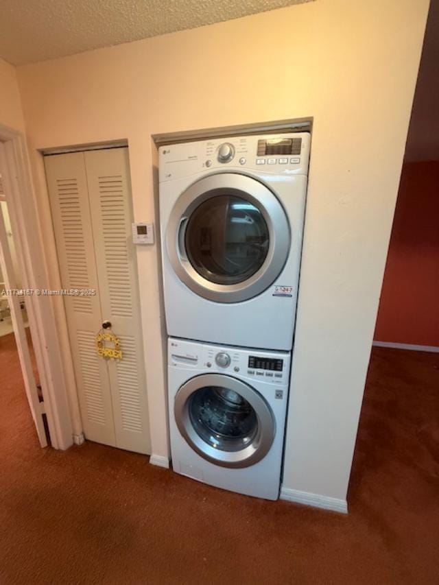 laundry area featuring stacked washing maching and dryer, dark carpet, and a textured ceiling