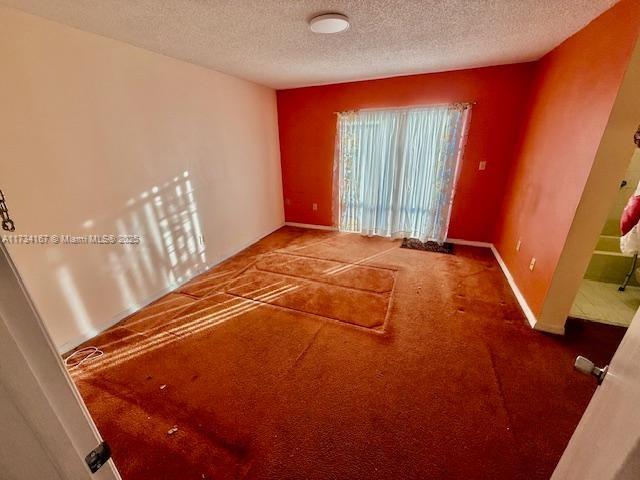 carpeted empty room featuring a textured ceiling