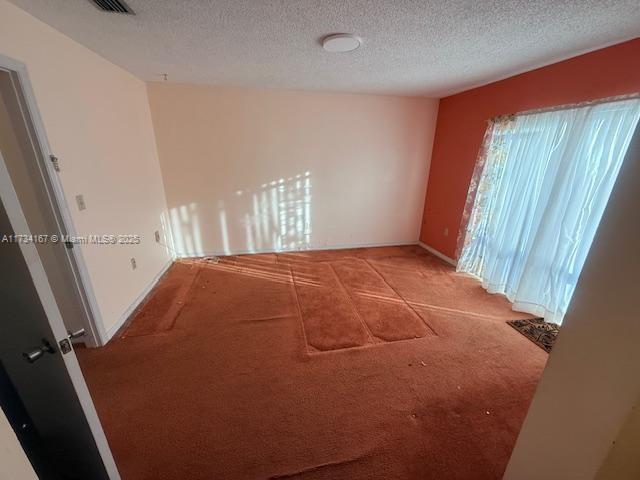 unfurnished room with light colored carpet and a textured ceiling