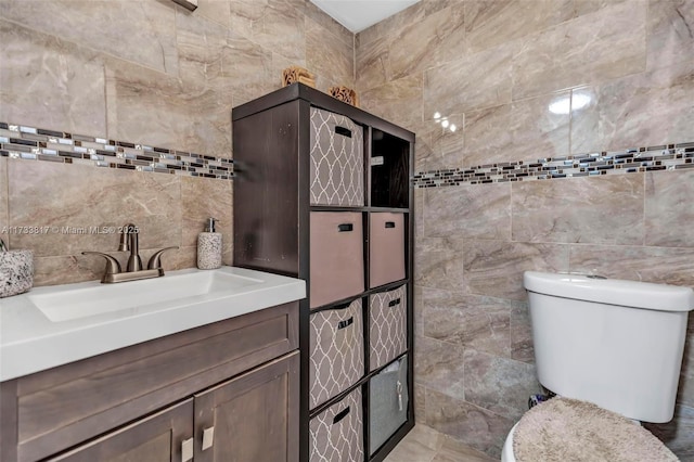 bathroom with vanity, toilet, and tile walls