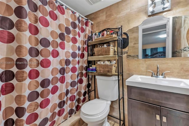 bathroom with tile walls, vanity, toilet, and a shower with shower curtain