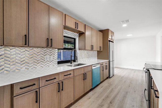 kitchen with tasteful backsplash, sink, stainless steel appliances, and light hardwood / wood-style floors