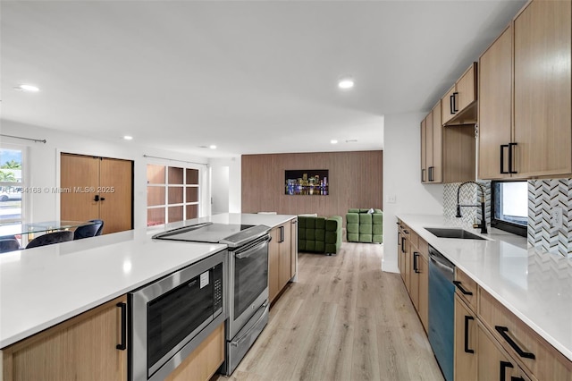 kitchen featuring decorative backsplash, appliances with stainless steel finishes, sink, and light hardwood / wood-style flooring