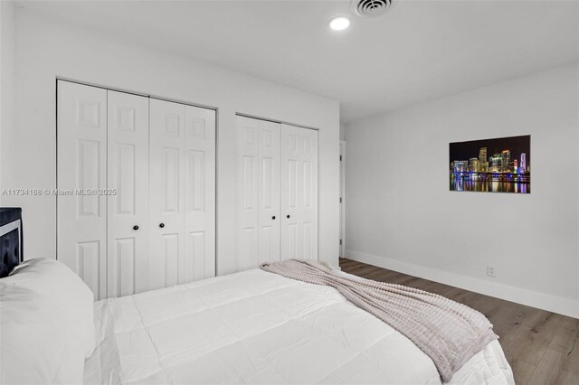 bedroom with dark hardwood / wood-style floors and two closets