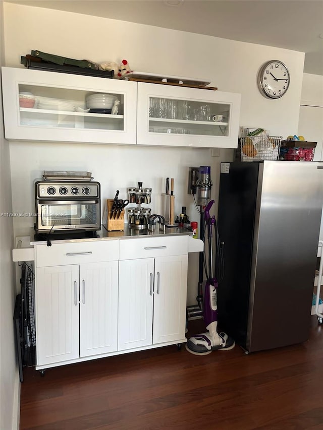 kitchen featuring stainless steel fridge, dark hardwood / wood-style floors, and white cabinets