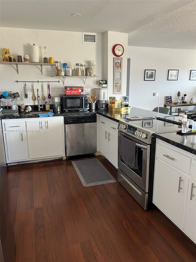 kitchen with white cabinetry, appliances with stainless steel finishes, dark wood-type flooring, and a textured ceiling