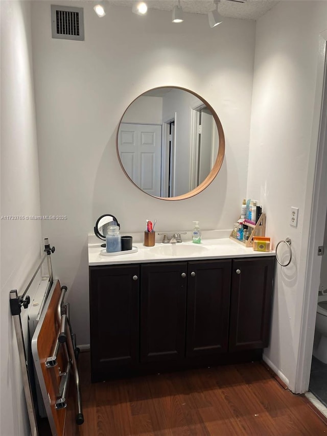 bathroom featuring wood-type flooring, toilet, and vanity