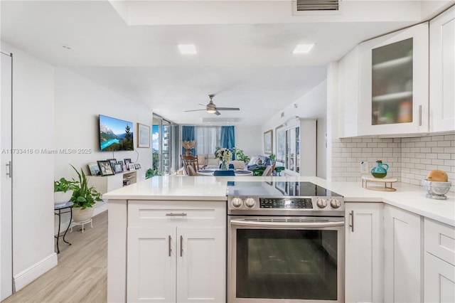 kitchen featuring white cabinetry, electric range, light hardwood / wood-style flooring, and decorative backsplash