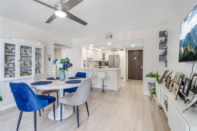 dining room featuring sink, ceiling fan, and light hardwood / wood-style flooring