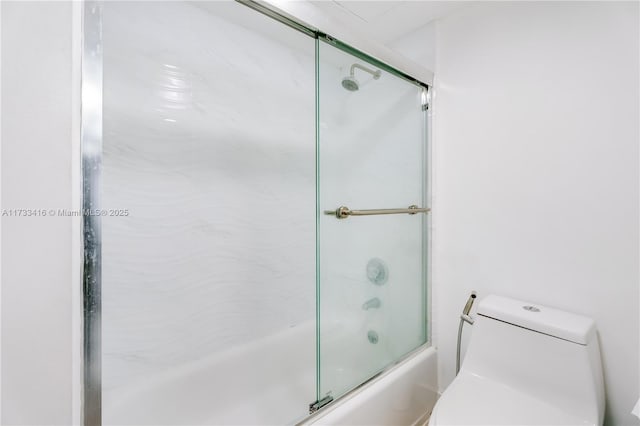 bathroom featuring bath / shower combo with glass door and toilet