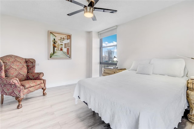 bedroom with ceiling fan, light hardwood / wood-style floors, and a textured ceiling