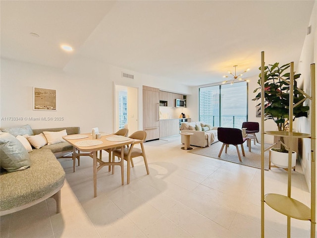 living area with expansive windows, an inviting chandelier, and visible vents