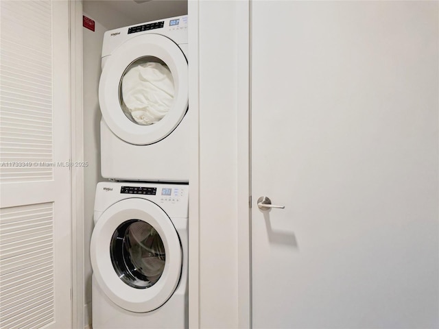 clothes washing area featuring stacked washer and clothes dryer and laundry area