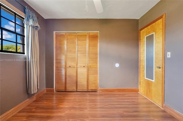 unfurnished bedroom with ceiling fan, a closet, and light wood-type flooring