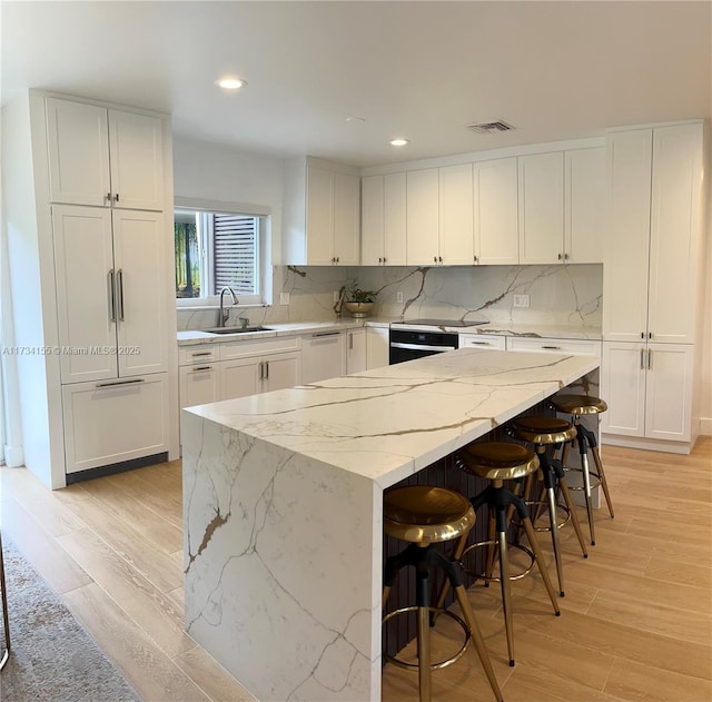 kitchen featuring white cabinetry, sink, and a center island