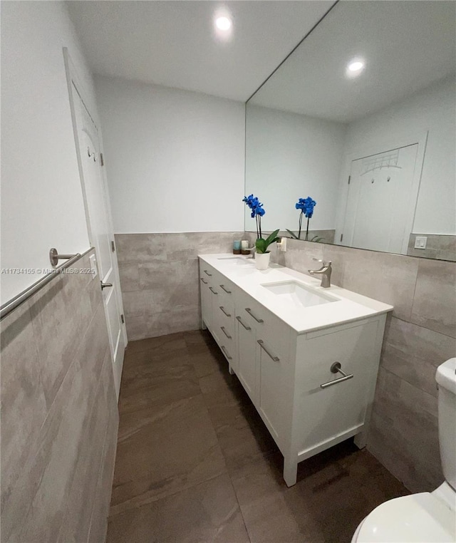 bathroom featuring vanity, toilet, tile patterned flooring, and tile walls