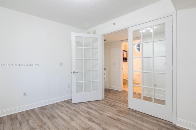 empty room featuring french doors and light hardwood / wood-style floors