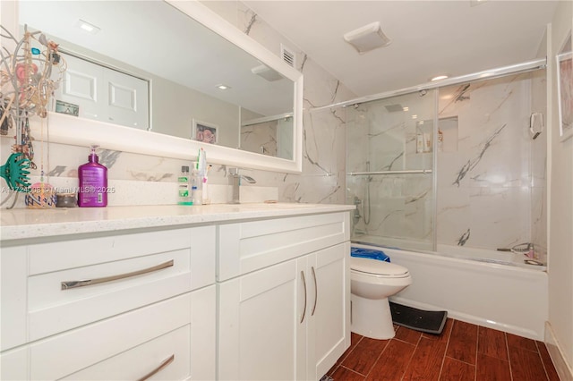 full bathroom with vanity, bath / shower combo with glass door, and toilet