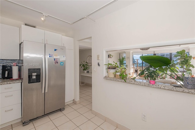 kitchen with stainless steel refrigerator with ice dispenser, light tile patterned floors, and white cabinets